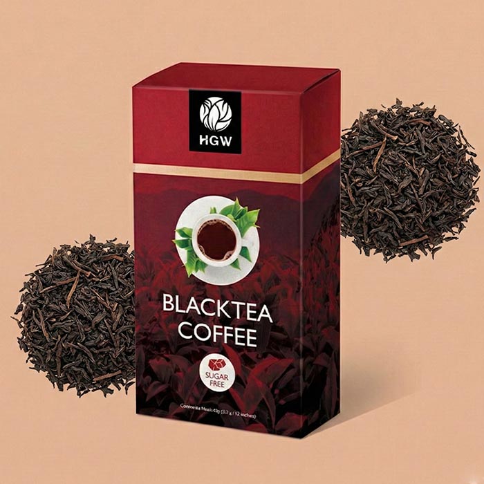 Caja de Black Tea Coffee HGW rodeada de té negro (camelia sinensis) en hebras secas.